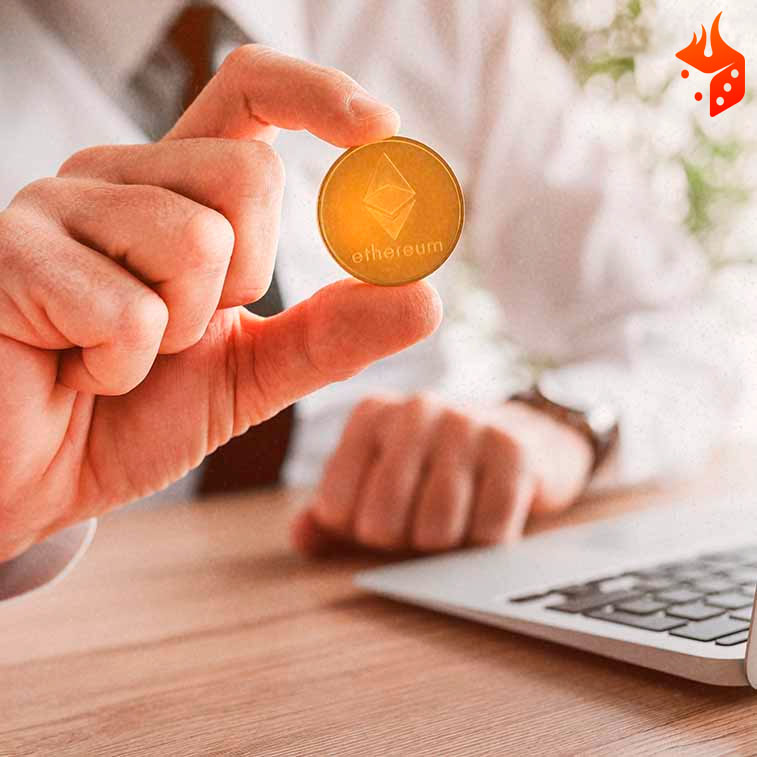 moneda criptomoneda ethereum Persona con una moneda de ethereum en la mano frente a una notebook.