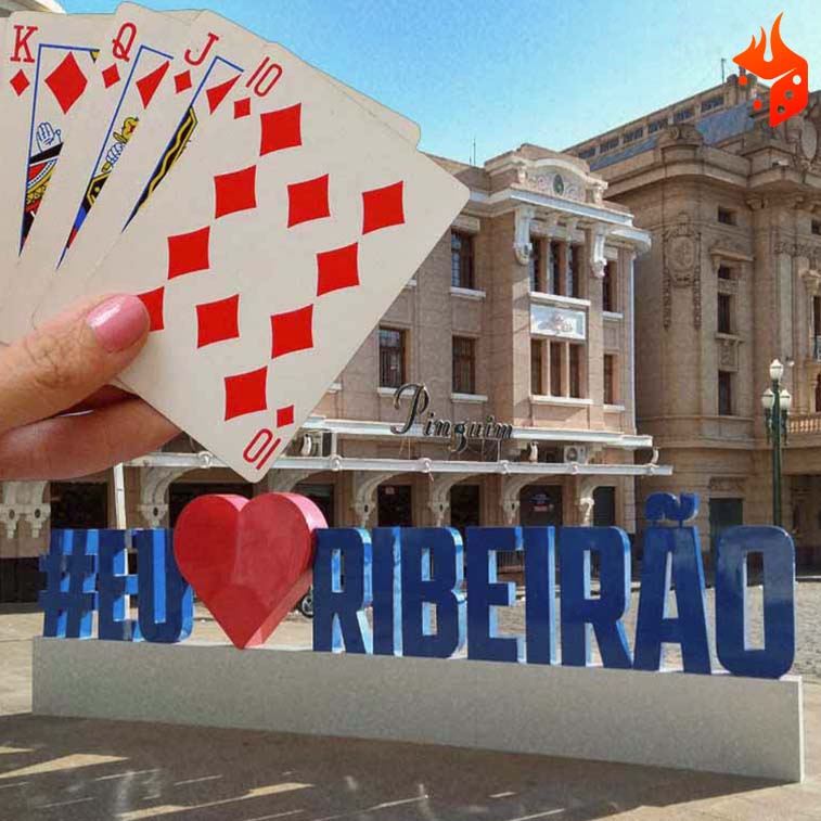 ribeirao preto poker Mão segurando cartas de poker e ao fundo, cartão postal da cidade com a frase “eu amo Ribeirão”